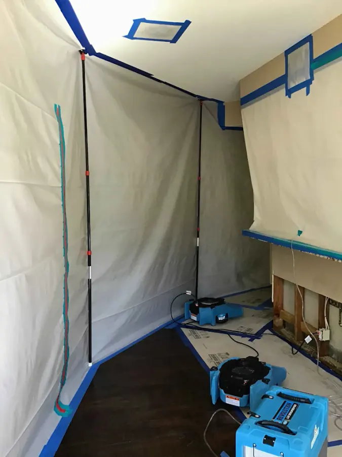 Hallway water damage containment with plastic sheeting, air movers, and flood cuts on lower walls