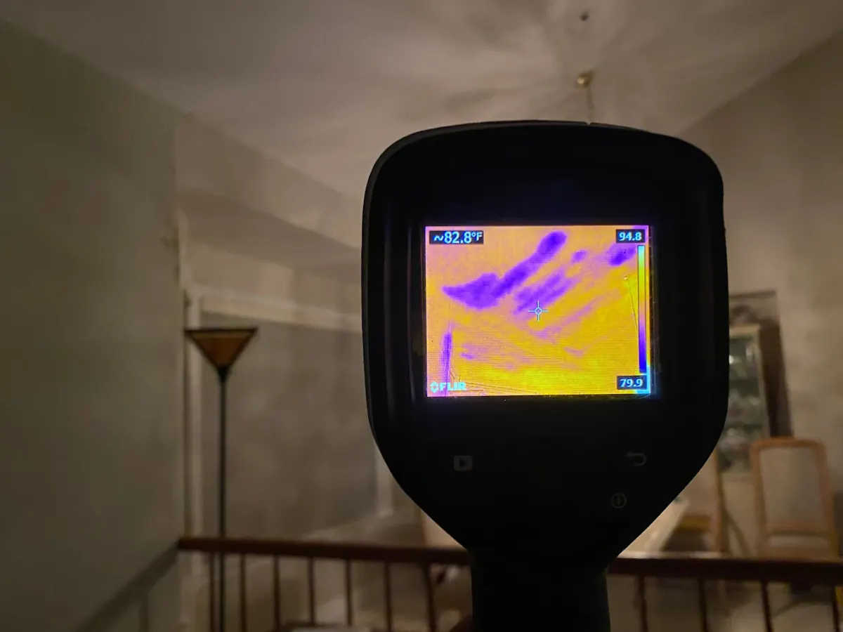 FLIR thermal camera detecting moisture patterns on ceiling during water damage inspection